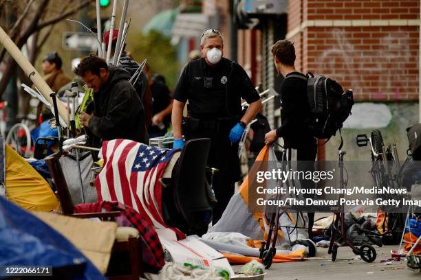 Denver Police officer Jon Udland, center, asks people packeting around the intersections of 22nd St. And Champ St. In Denver, Colorado on Thursday....