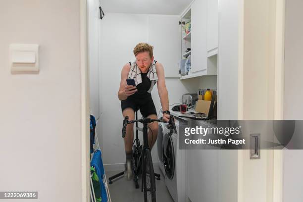 man using turbo trainer in utility room - blur sports technology stockfoto's en -beelden
