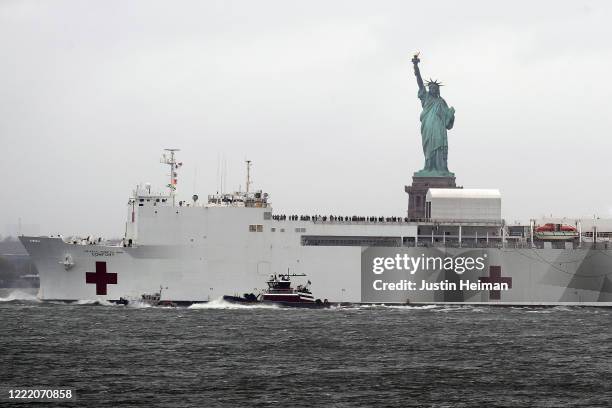 The USNS Comfort hospital ship exits the harbor in front of the Statue of Liberty as it heads back to Naval Station Norfolk in Virginia on April 30,...