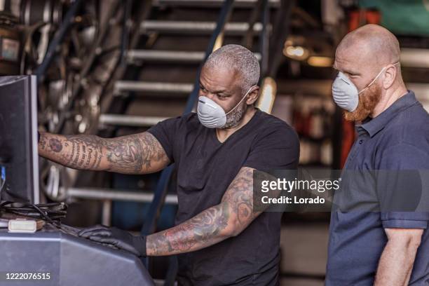 Two male mechanic essential workers wearing a face mask each during virus outbreak