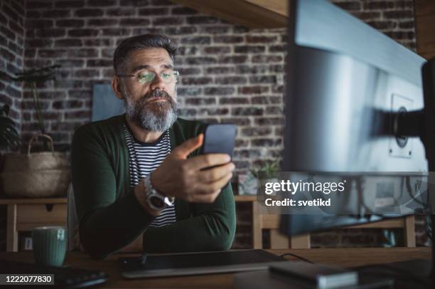 working from home during isolation period - mature man using phone tablet stock pictures, royalty-free photos & images