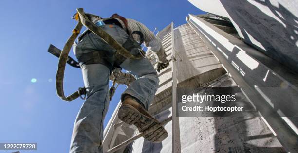 en oljefält worker klättrar en stege på sidan av en mud tank på en olja och gas drilling pad site på en solig morgon - förvaringstank bildbanksfoton och bilder