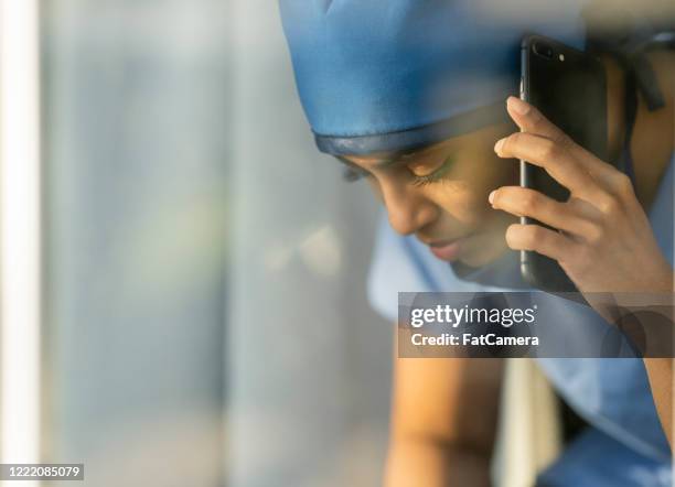 müde arzt aus dem nahen osten, der eine pause eingeht, um einen geliebten menschen anzurufen - op-mundschutz stock-fotos und bilder