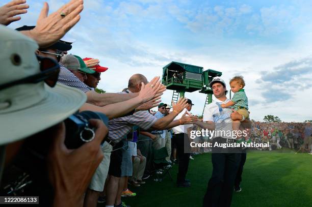 Masters champion Bubba Watson reacts with patrons as he holds son Caleb after winning the Masters during the final round at Augusta National Golf...