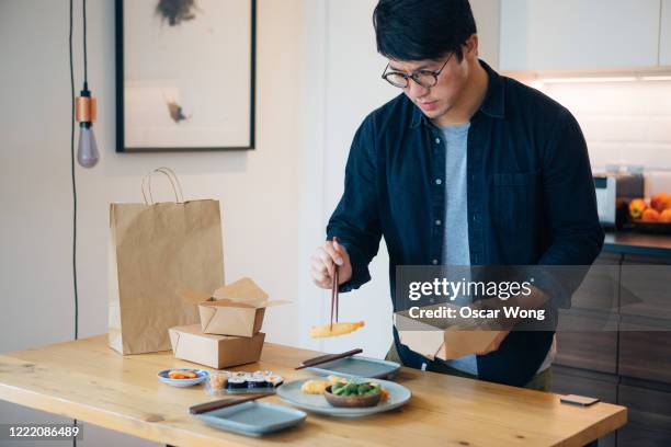 young man placing takeaway food on plate - japanese chopsticks stock pictures, royalty-free photos & images