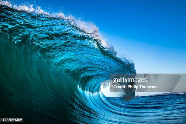 ola chocando en el océano con cielo azul - ola fotografías e imágenes de stock
