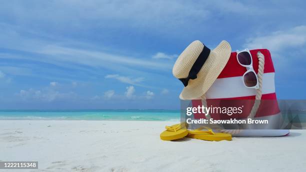 tourism and travel, tropical vacation concept, striped beach bag flip-flops glasses and children toy on white sand beach. family vacation background - around the world background stock pictures, royalty-free photos & images