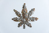 A marijuana leaf made of US American coins on solid white background with blank empty room space for copy, text, or copyspace. Taxing cannabis may bring economic revenue in the USA.