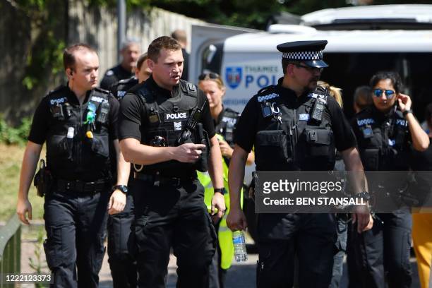 Police officers congregate outside a cordoned off block of flats where the suspect of a multiple stabbing incident lived in Reading, west of London,...