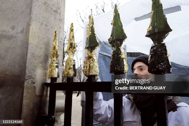 Un jeune homme procède à la restauration des flèches d'une grille du jardin du Palais Royal, le 18 décembre 2008 à Paris. AFP PHOTO BERTRAND GUAY