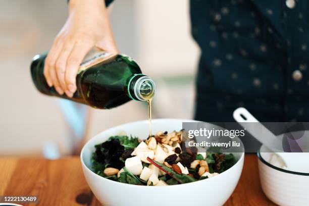 homemade gourmet food: fresh green salad with mozzarella, mixed nuts and dry fruits - olijfolie stockfoto's en -beelden