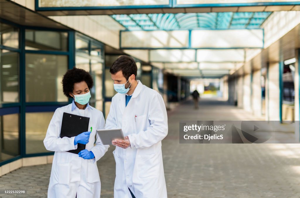 Two doctors looking at medical results on digital tablet.