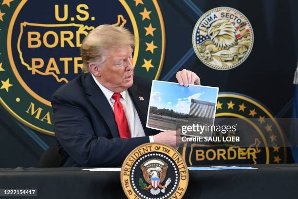 President Donald Trump shows a photo of the border wall upon arrival at the US Border Patrol station in Yuma, Arizona, June 23 as he travels to visit...