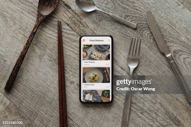 ordering food by mobile app delivery on smartphone - smartphone cuisine stock-fotos und bilder