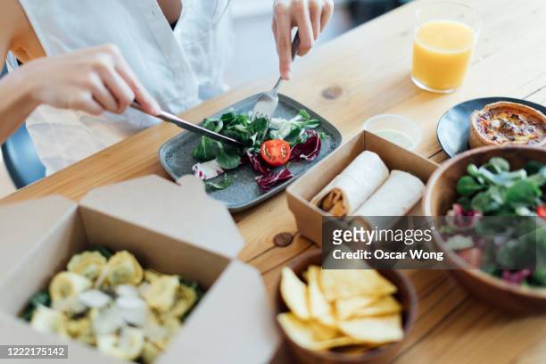 young woman eating healthy takeaway meal at home - sack lunch stock pictures, royalty-free photos & images