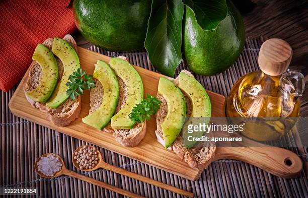 snack or appetizer of avocado slices bruschetta with olive oil, peppermint and salt - aguacates stock pictures, royalty-free photos & images
