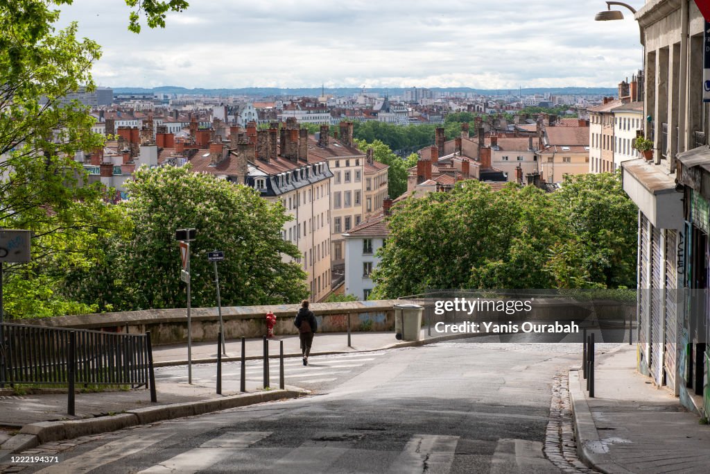 Single woman walking alone in a small street with a panoramic view of Lyon, in the Croix-Rousse district, Lyon, France, during Coronavirus lockdown, april 2020