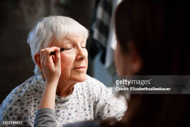 girl putting make-up on her grandmother - 70s eye makeup stockfoto's en -beelden