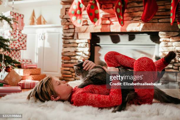 boy lying on a fluffy rug stroking his cat - kid with cat stock-fotos und bilder