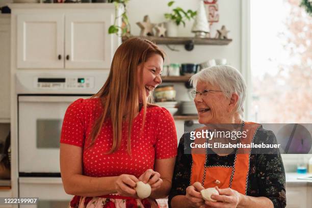 senior woman teaching her daughter to make bread - woman front and back stock-fotos und bilder