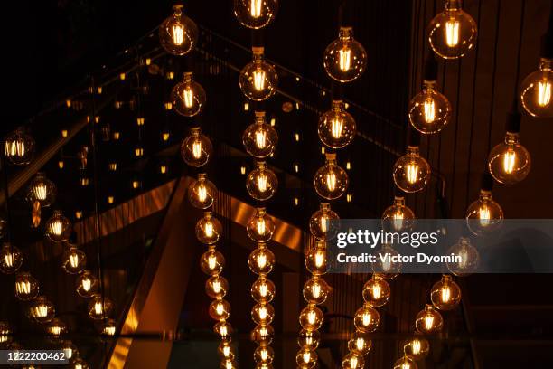 round yellow bulbs hang in rows on a dark background - lamp shade fotografías e imágenes de stock