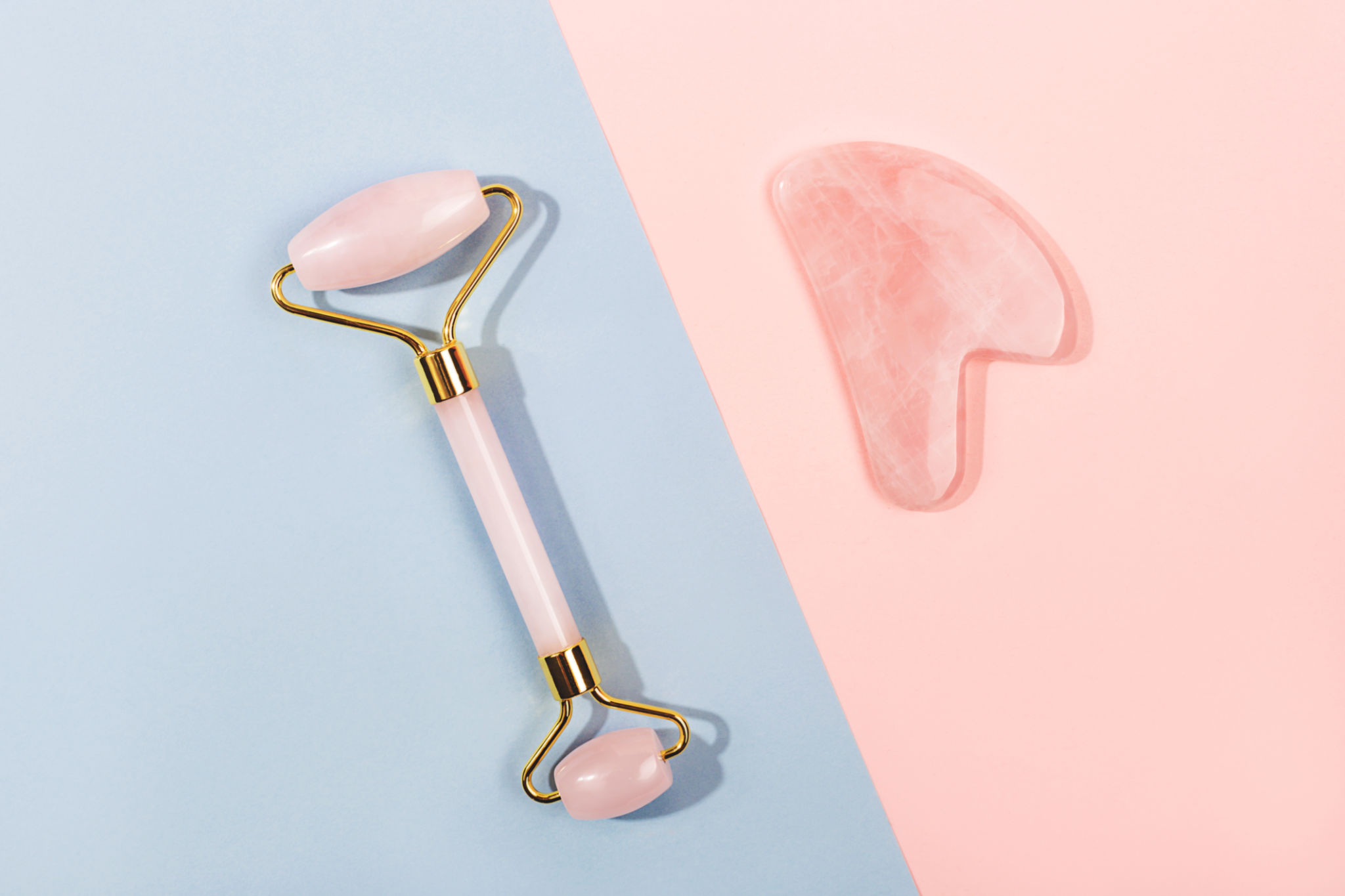 Pink jade roller and gua sha tool on pastel background. Pink jade roller and gua sha tool on pastel background.
