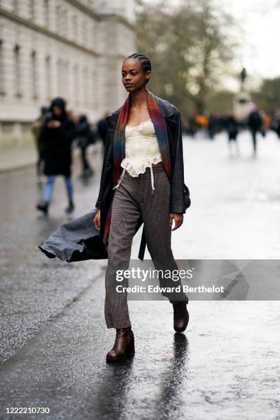 Model wears a black leather jacket a colored scarf, gray pants, black leather shoes, during London Fashion Week Fall Winter 2020 on February 16, 2020...