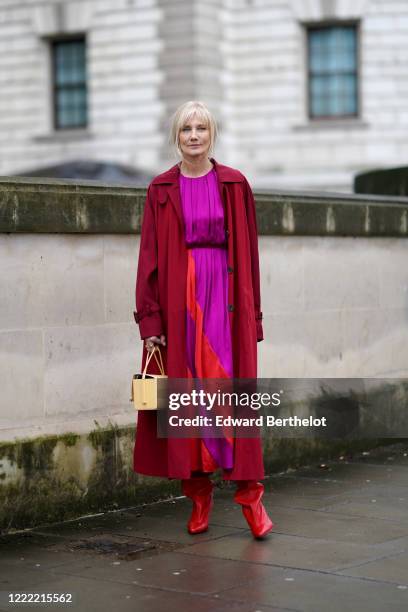 Joely Richardson wears a red long coat, a neon purple lustrous dress with a large red stripe, a pastel yellow bag, red leather pointy boots, during...