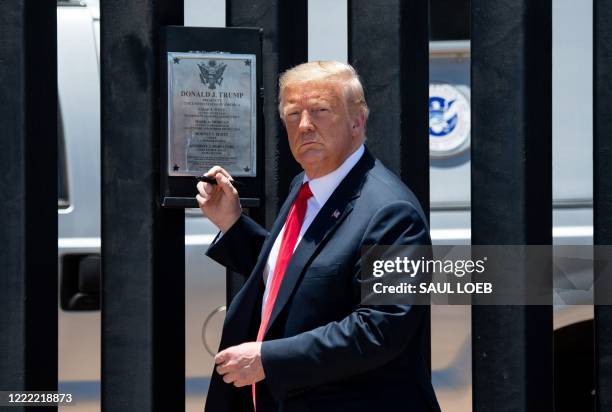 President Donald Trump looks on before signing a plaque as he participates in a ceremony commemorating the 200th mile of border wall at the...