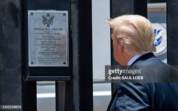 President Donald Trump looks at a plaque before signing it as he participates in a ceremony commemorating the 200th mile of border wall at the...