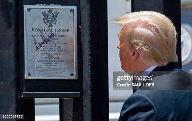 President Donald Trump looks at a plaque after signing it as he participates in a ceremony commemorating the 200th mile of border wall at the...