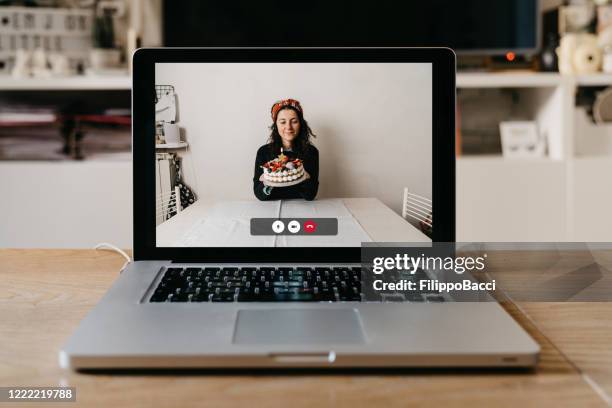 a laptop with a woman and her birthday cake on the screen - zoom birthday stock pictures, royalty-free photos & images