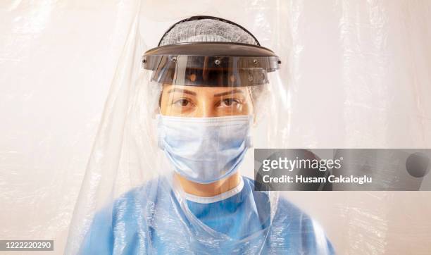 woman doctor looking at camera behind isolated curtain - welding mask stock pictures, royalty-free photos & images