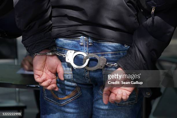 Demonstrator wears handcuffs following his arrest after he took part in a protest against government lockdown measures on May Day during the novel...