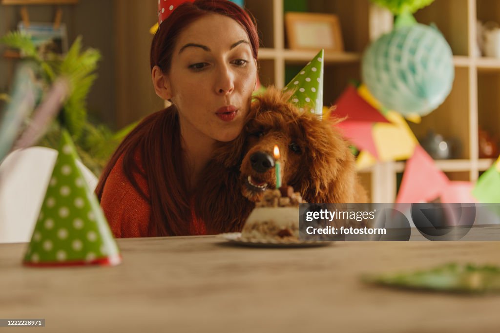 Owner blowing her dog's birthday candle while celebrating his first birthday