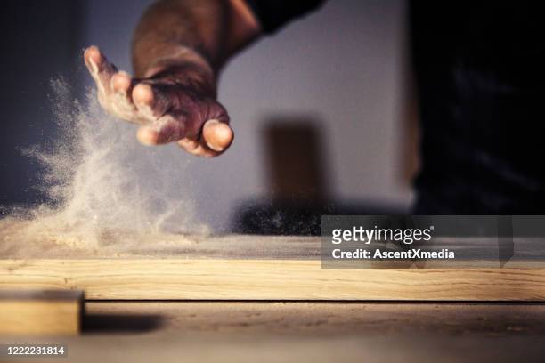 carpenter brushes wood dust off table - carpenter imagens e fotografias de stock