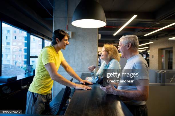 retired couple signing up to the gym and looking happy - gym receptionist stock pictures, royalty-free photos & images
