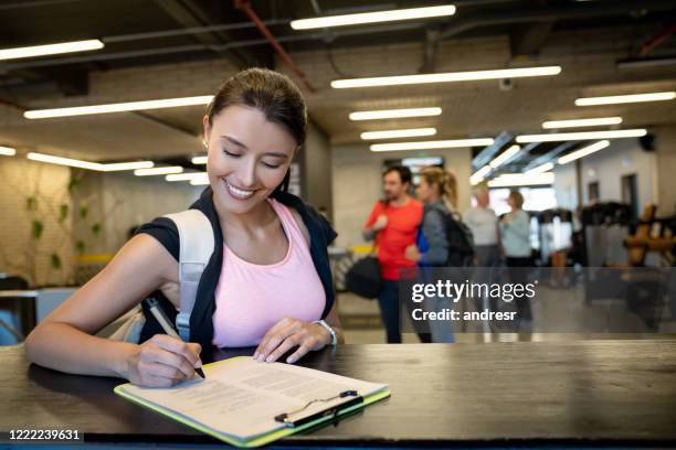 happy woman signing up to the gym - subscription stock pictures, royalty-free photos & images