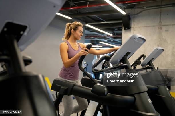 woman at the gym exercising on a cross trainer - happy caucasian woman on elliptical trainer at gym stock pictures, royalty-free photos & images