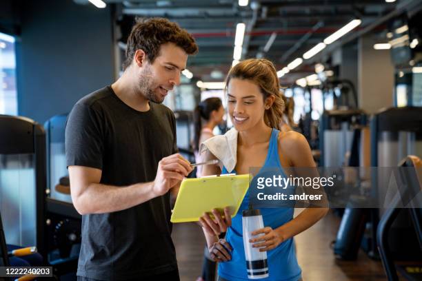 entrenador personal trabajando en el gimnasio y hablando con una joven - instructor de acondicionamiento físico fotografías e imágenes de stock