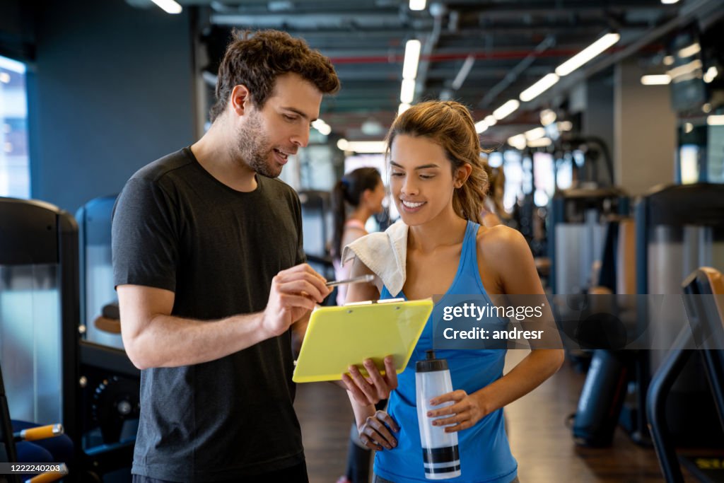 Personal trainer working at the gym and talking to a young woman