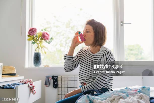 woman with pink asthma inhaler - asthma in adults stock pictures, royalty-free photos & images