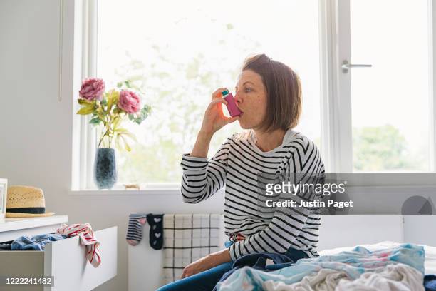 woman with pink asthma inhaler - asthma in adults imagens e fotografias de stock