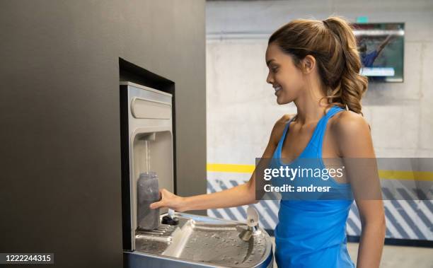 donna in palestra che riempie la sua bottiglia d'acqua - filling foto e immagini stock