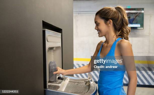 kvinna på gymmet fyller upp sin vattenflaska - filling bildbanksfoton och bilder