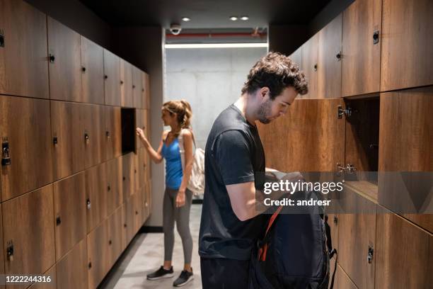 menschen in der umkleidekabine des fitnessstudios legen ihre sachen in den spind - spind stock-fotos und bilder