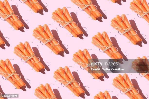 repeated bunch of carrots on the pink background - ベビーキャロット ストックフォトと画像