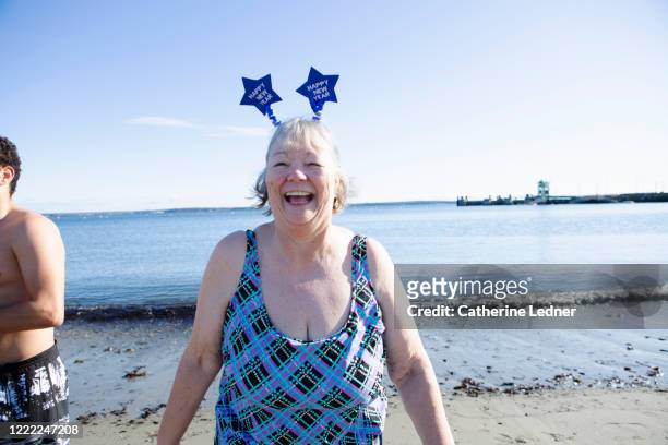 Older woman in bathing suit laughing and wearing a headband with stars