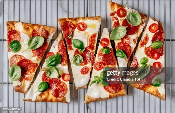 slices of pizza on cooling rack on white background - salami stock pictures, royalty-free photos & images