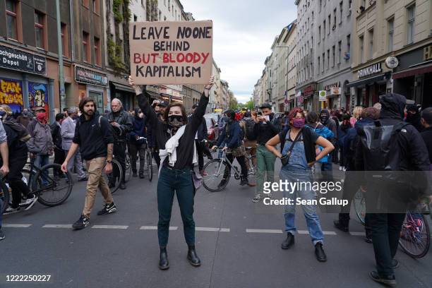 An activist holds up a sign against capitalism during scattered left-wing protests in Kreuzberg district on May Day during the novel coronavirus...